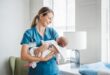 A person in blue scrubs holding a baby Description automatically generated